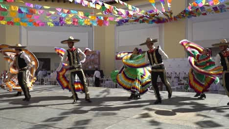 men and women dancing in mexico with colorful costumes on a sunny day