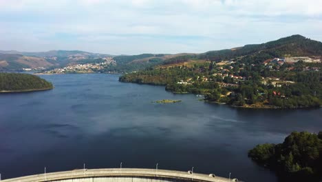 car going through dam in northern portugal, backwards drone aerial shot with river and forest