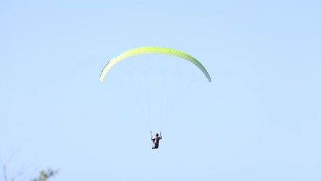 solo paraglider flying against a clear blue sky