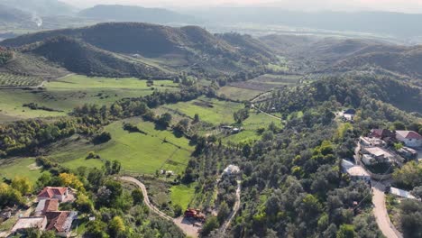 areal shot of village houses and farmland with planted fields and greenhouses