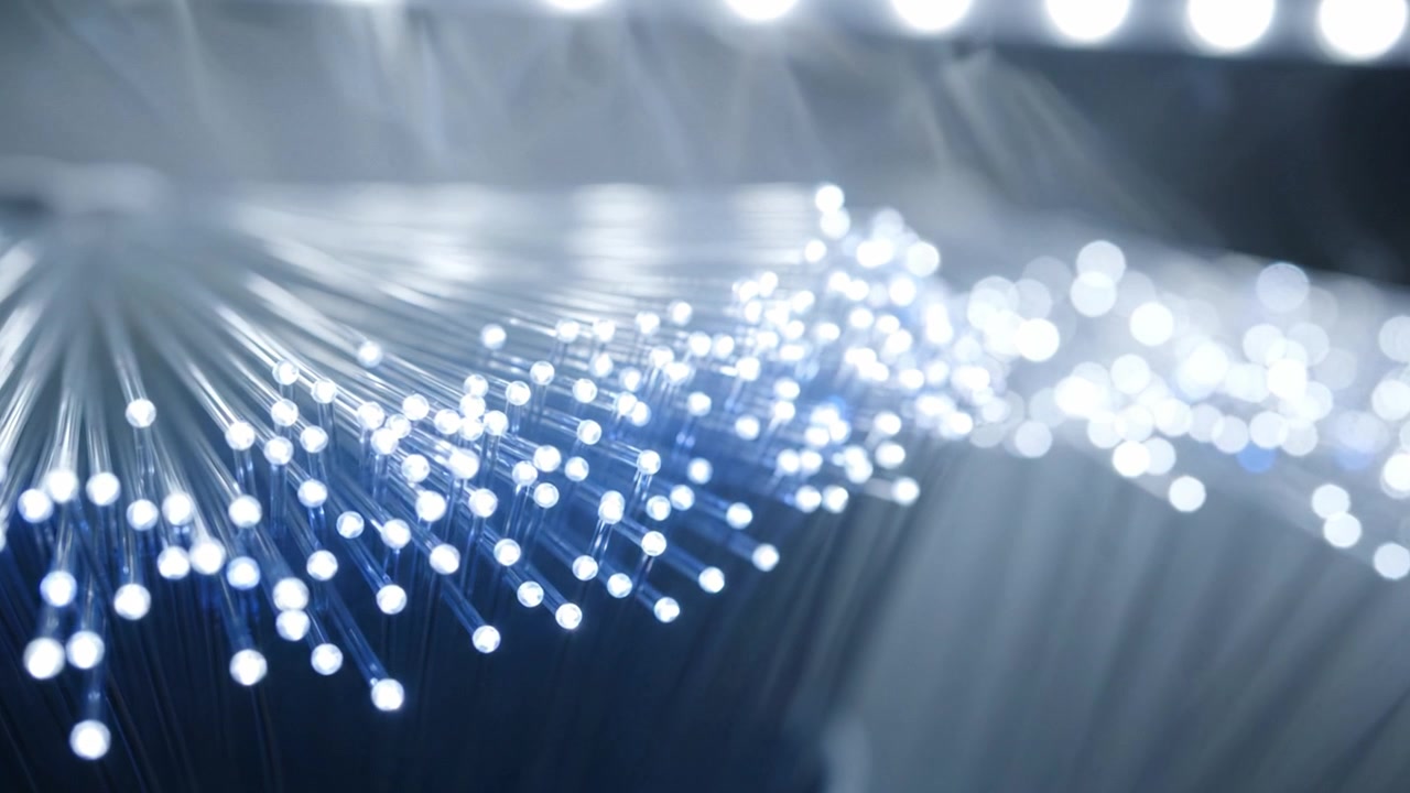 Belyste fiberoptiske kabler, der glimter med lys, og viser de indviklede detaljer af moderne kommunikationsteknologier og deres indvirkning på forbindelse.