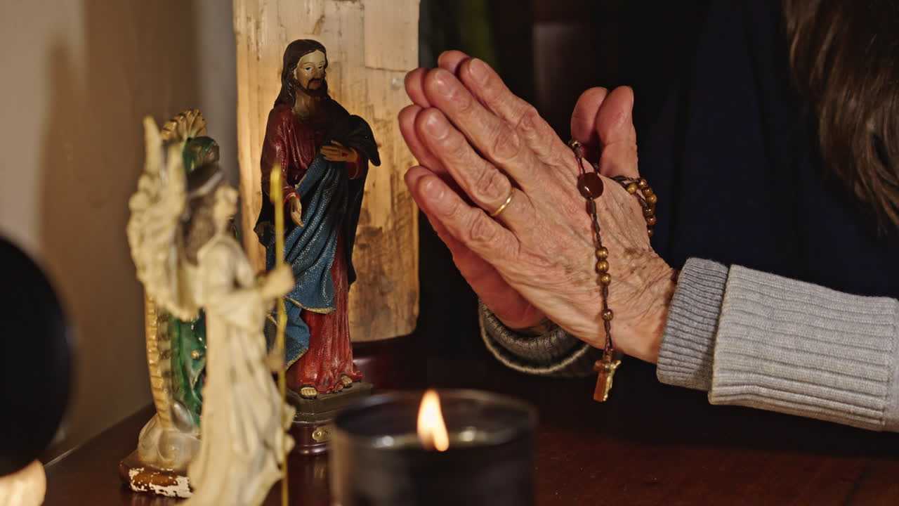 Elderly Person's Hands Praying with Rosary and Candle