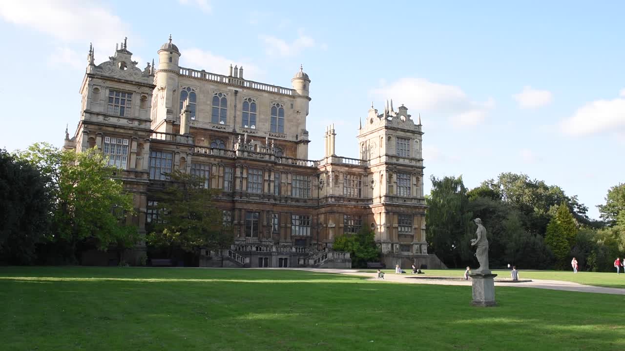 View of people walking through Wollaton Park in Nottingham, England, with the magnificent Wollaton Hall in the background. The Wollaton Hall is one of Nottingham’s most famous historic landmarks