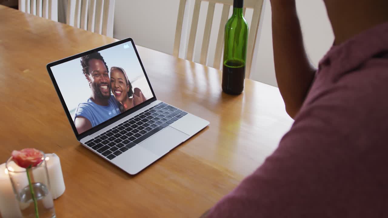 Mid section of african american man drinking wine while having a video call on laptop at home