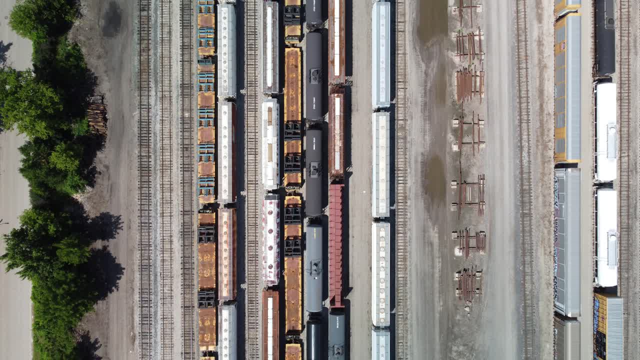 Oil train tankers slowly moving along the train tracks, aerial footage of a large train yard