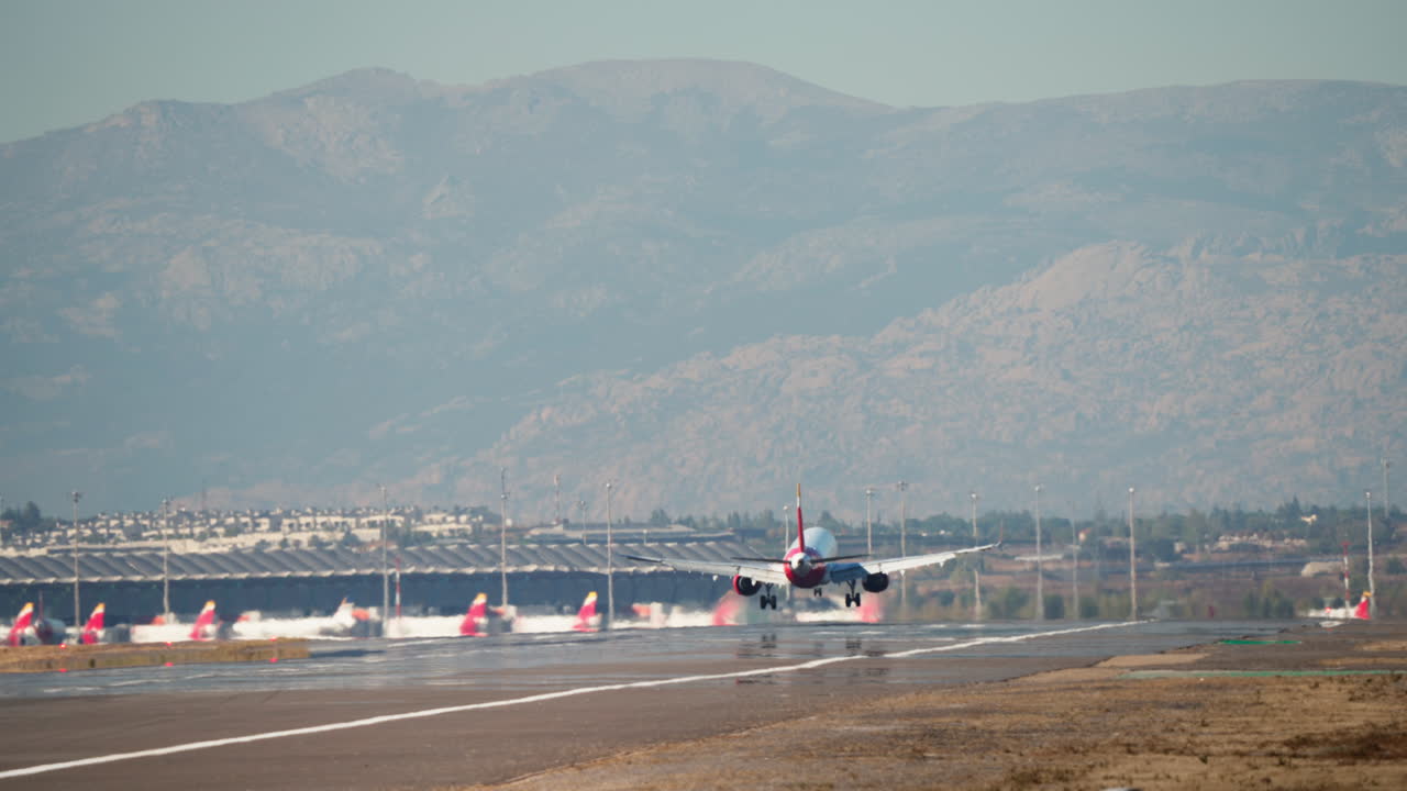 Grande aereo passeggeri in atterraggio sulla pista dell'aeroporto con montagne