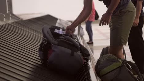 man collecting rucksack from baggage claim