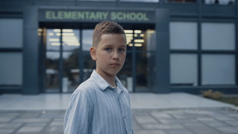 Upset-elementary-age-boy-standing-at-schoolyard-closeup.-Portrait-unhappy-pupil.