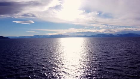 A-beautiful-aerial-drone-shot,-flying-over-crystal-clear-water-towards-the-mountains-in-Lake-Tahoe,-Nevada-California