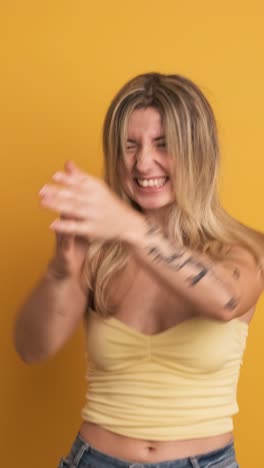 smiling and jumping young woman with raised hands on yellow background