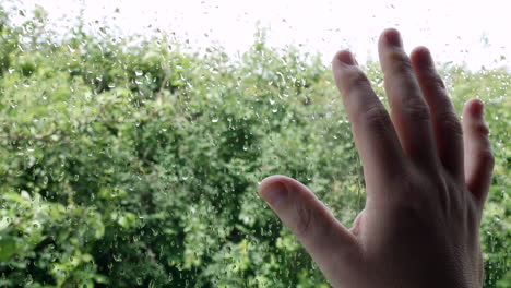 a man with his hand on a window with rain outside