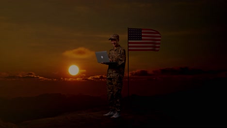 full body of side view asian man soldier using a laptop while standing with flag of the united states, sunset time