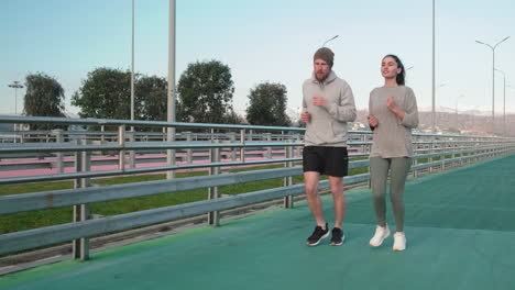 una pareja corriendo por un puente de la ciudad.