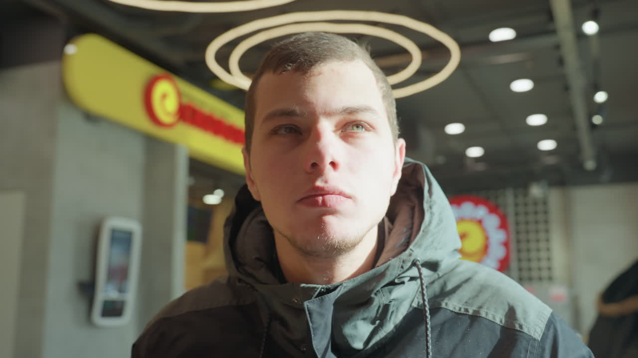 Giovane uomo bianco in un caffè che chiude gli occhi ed espira, pendolare che fa una pausa durante il turno mattutino con vapore caldo che sale dalla tazza, luce ad aureola sopra la testa, momento tranquillo e introspettivo, interni urbani e bagliore soffuso