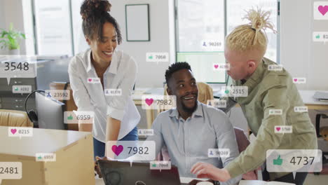 anmation of social media icons against diverse colleagues discussing over a laptop at office