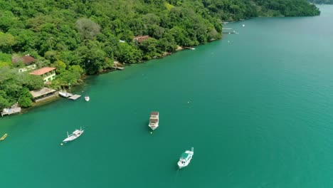 drone aéreo voa de barco perto da costa de uma ilha com muita vegetação e floresta tropical verde