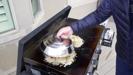 Sprinkling-cheese-on-top-of-the-eggs-and-potatoes-to-make-a-hash-brown-omelet