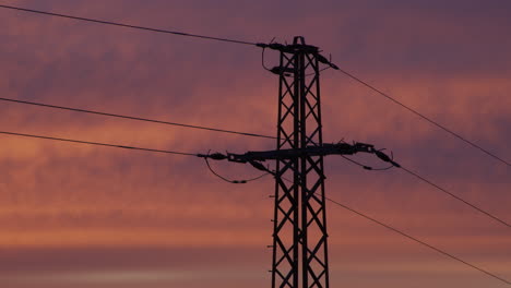 plano medio de una torre de electricidad al amanecer