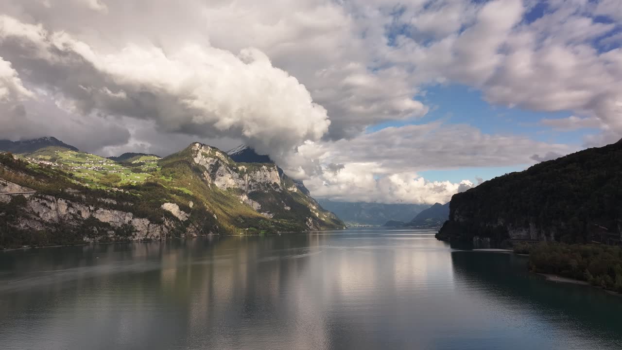 Aerial view of Lake Walensee in Switzerland, reflecting clouds and surrounding mountains on its tranquil waters. The harmonious beauty of nature's reflections.