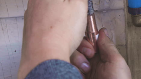 panning shot of a man's hands fitting a coupler to a copper water pipe before soldering