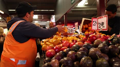 vendor arranging fruits at a busy market stall