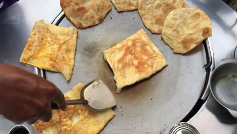 cocinar panqueques tailandeses exóticos, roti malaysian con diferentes rellenos en un mercado de tailandia. hacer rollo de roti de huevos en sartenes de metal calientes con aceite hervido. comida callejera de tailàndia. postre tailandés.