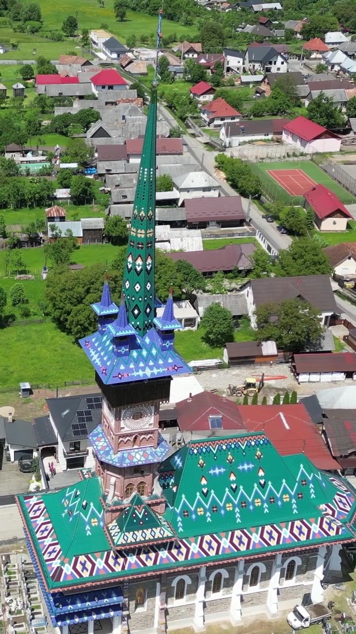 Drönarfilm som cirklar runt den färgglada kyrkan och livfulla målade träkors på den Glada Kyrkogården (Cimitirul Vesel) i Sapanta, Rumänien.