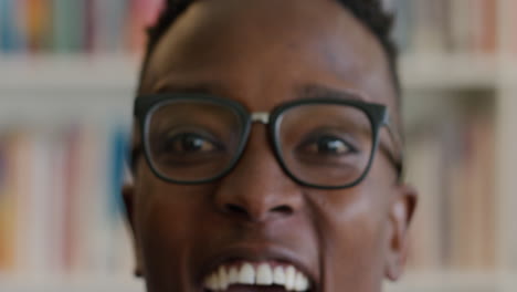 Portrait-happy-african-american-young-man-student-smiling-in-front-of-bookshelf