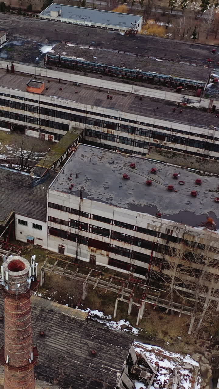 Old industrial zone with ruined buildings. Empty abandoned factory with brick edifices in place. Large aged enterprise. Top view. Vertical video