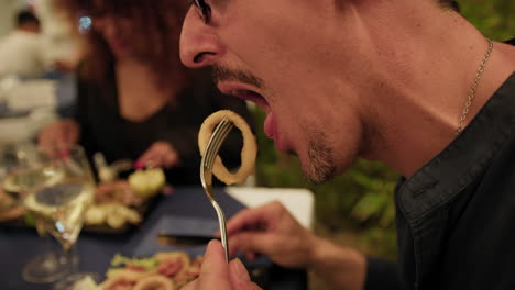 man eating fried squid rings during a romantic dinner at the restaurant