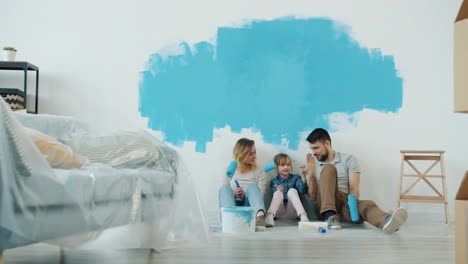 family painting a wall together in their new home.