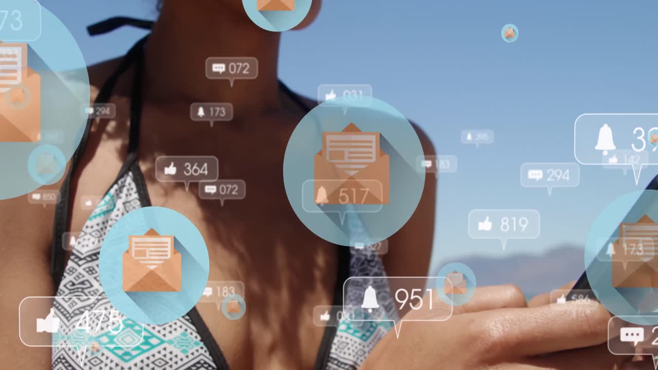 Social media icons floating against african american woman using smartphone at the beach