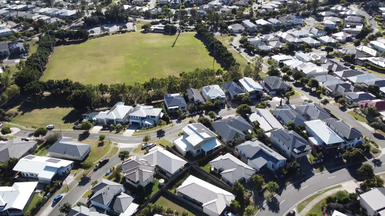 4K Drone footage of an Australian neighbourhood with large family homes and a sporting field