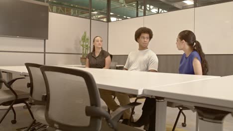 african american male in his 20's, arab american female in her 20's and caucasian female in her 20's in a meeting with video moving right to left