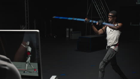 Hombre-Mocap-Con-Traje-De-Captura-De-Movimiento-En-El-Estudio-Interpretando-Al-Personal-Bo-Lucha-Con-Espada-Actor-De-Artes-Marciales-Con-Traje-Mo-cap-Para-Animación-De-Personajes-3d-Para-La-Industria-De-Juegos-De-Realidad-Virtual