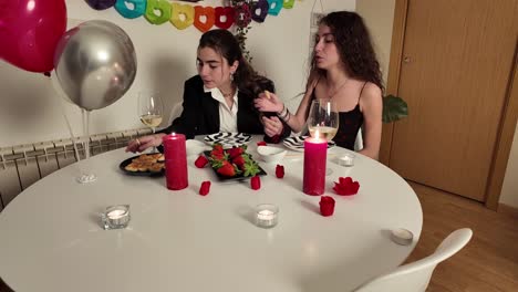 two women celebrating with a dinner and balloons
