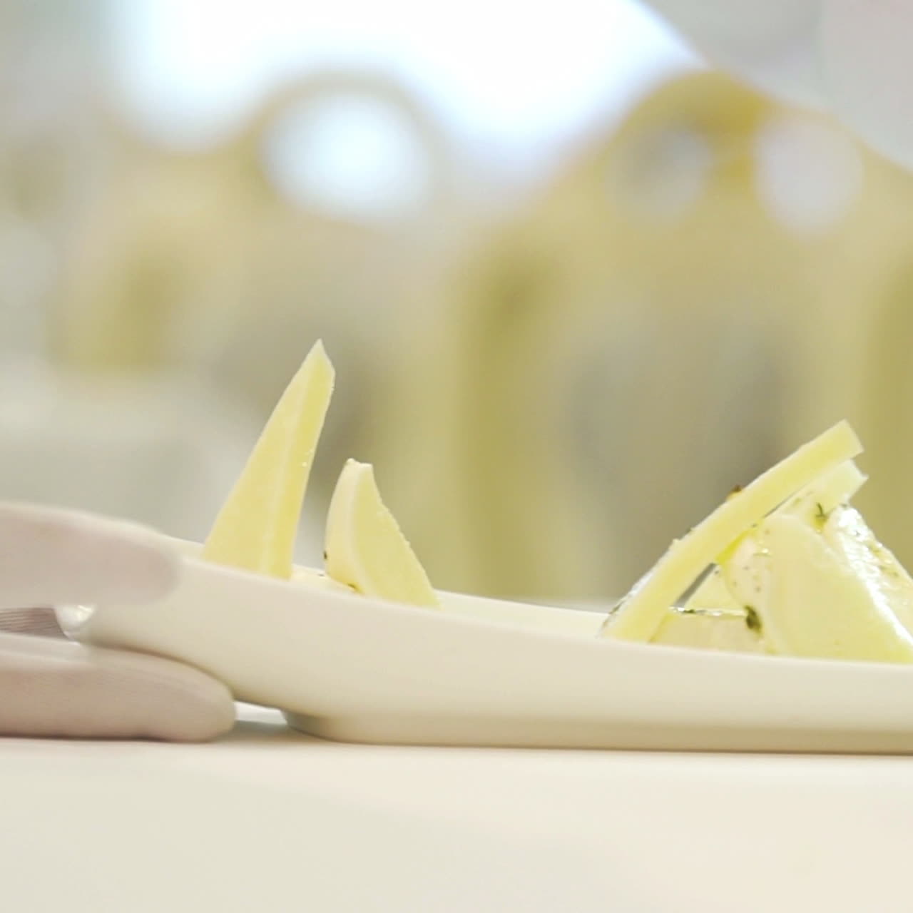 A chef adds delicious sauce to triangular pieces of hard cheese with feta inside on a white plate at a festive table in the restaurant for guests. Close-up.
