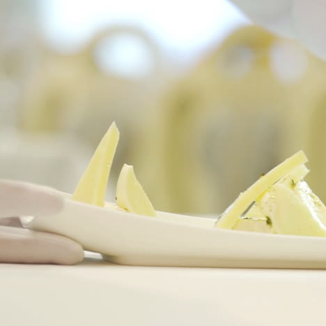 a chef adds delicious sauce to triangular pieces of hard cheese with feta inside on a white plate at a festive table in the restaurant for guests. close-up.