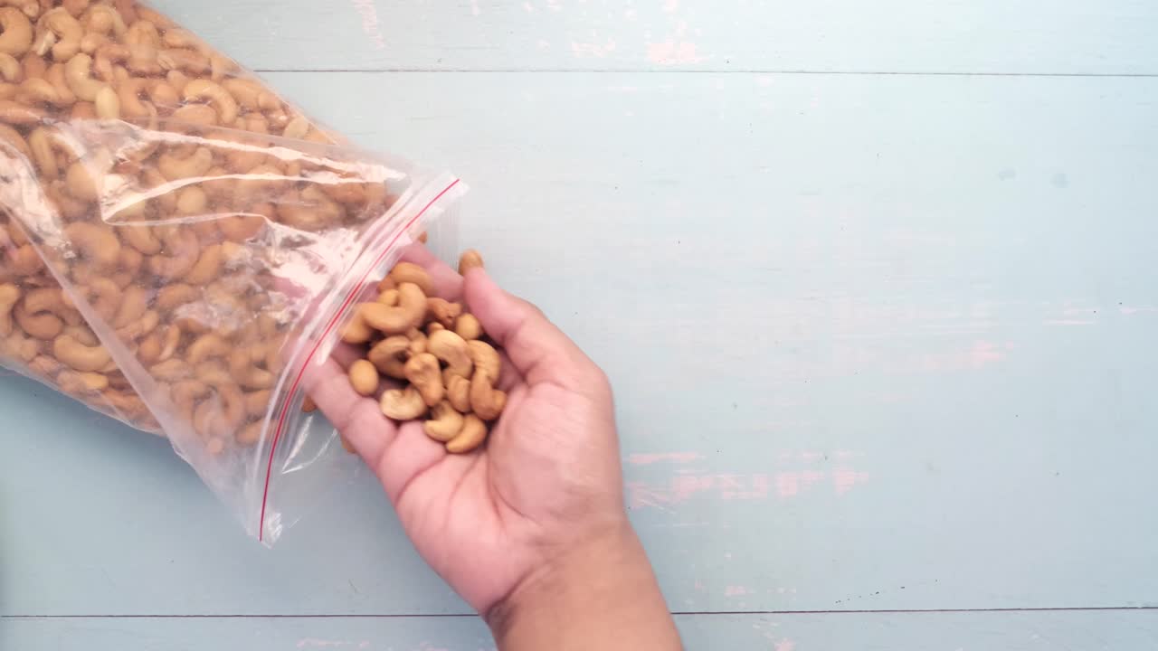 mano metiendo la mano en una bolsa de plástico de caju