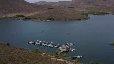 A-beautiful-aerial-drone-shot,-drone-flying-over-a-marina-towards-the-mountain-lines-in-Lake-Skinner---Temecula---Riverside-County---California