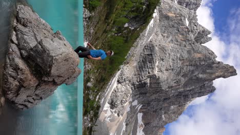 hombre feliz en el lago di sorapis abriendo los brazos mirando a dito di dio, italia