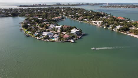 Drone-clip-moving-towards-shoreline-and-panning-downwards-towards-a-luxurious-house-with-a-boat-jetty