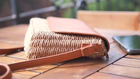 a close-up of a brown woven handbag with a leather strap on a wooden table