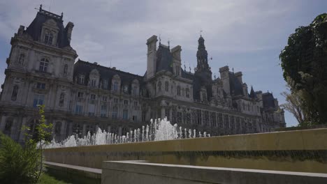 Exterior-Del-Hotel-De-Ville-En-París,-Francia,-Con-Fuentes-En-Primer-Plano-En-Cámara-Lenta.