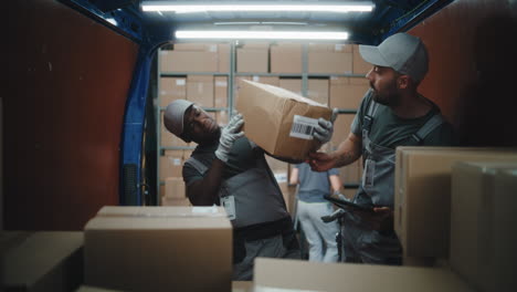 delivery or warehouse workers handling packages and using a tablet inside a van