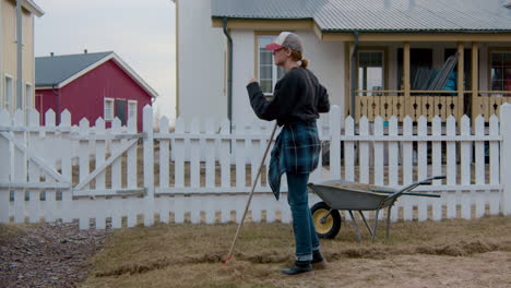 woman sweeping leaves in front of house