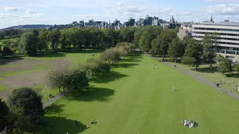 an aerial shot moving across the meadows in edinburgh, on a sunny summer day