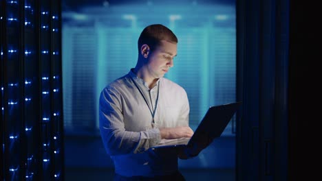 concepto de digitalización de la información: es especialista en frente de los racks de servidores con portátil, activa el centro de datos con un gesto de tacto. trabajando en un portátil de pie antes de abrir el gabinete de rack de servidor