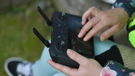 female hands setting with fingers parameters for photogrammetry on drone remote controller with double antenna