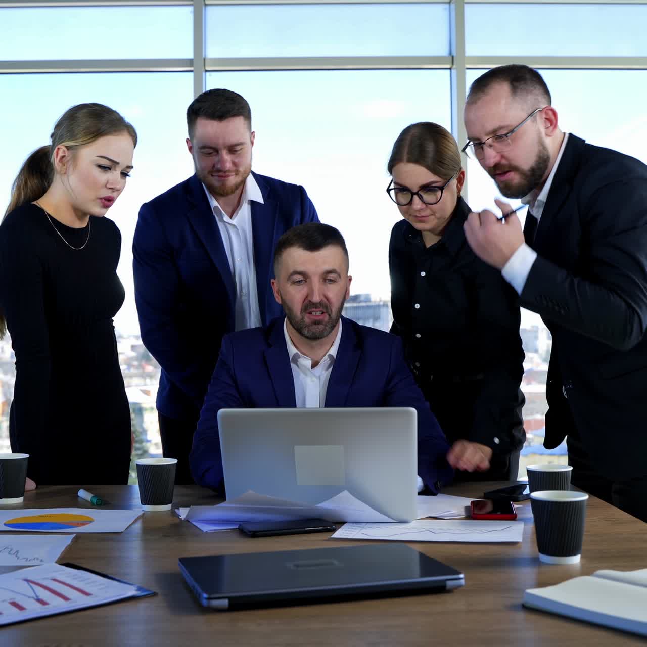 Teamwork of businessmen. Group of entrepreneurs in elegant clothes work together on a project in front of a laptop in office centre